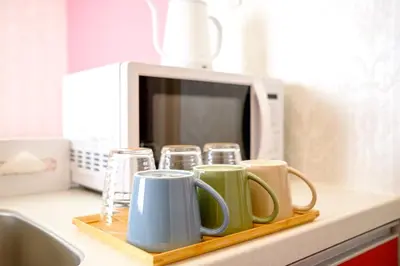 a tray with mugs on a counter next to a microwave at ViLLA SAKURA \u6771\u4eac\u76ee\u9ed2 in Tokyo