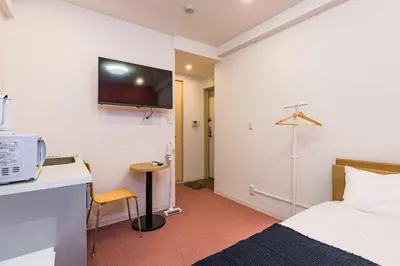 a hotel room with a bed and a tv on the wall at ViLLA SAKURA \u6771\u4eac\u76ee\u9ed2 in Tokyo