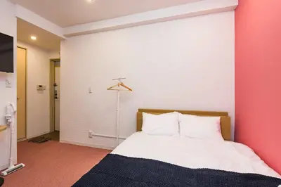 a bedroom with a bed with a pink wall at ViLLA SAKURA \u6771\u4eac\u76ee\u9ed2 in Tokyo