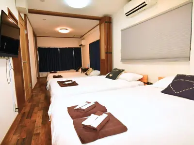 a hotel room with three beds and a television at \u5bae\u5143in\u6d45\u8349\u96f7\u9580\u6d45\u8349\u5bfa\u305d\u3070\u306e\u4e00\u8ed2\u5bb6\u306e\u304a\u90e8\u5c4b1\u968e\u53c8\u306f2\u968e in Tokyo