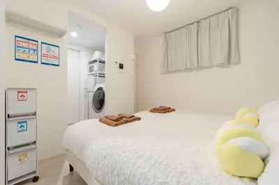 a bedroom with a bed and a washing machine at \u30a2\u30f3\u30c9\u30b9\u30c6\u30a4\u5927\u68ee\u4e2d102 in Tokyo