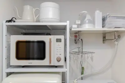 a microwave on a shelf with dishes on it at \u30a2\u30f3\u30c9\u30b9\u30c6\u30a4\u5927\u68ee\u4e2d102 in Tokyo