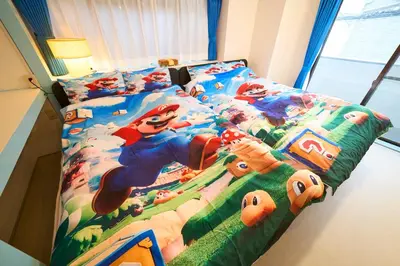 a bedroom with a bed with a disney themed bedspread at Yotsugi House \u56db\u30c4\u6728\u30cf\u30a6\u30b9 in Tokyo
