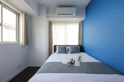 a blue bedroom with a bed with a blue wall at \u30b9\u30de\u30fc\u30c8 ViLLA \u65d7\u306e\u53f0I\u756a\u9928 in Tokyo