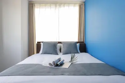 a bed with two towels and a book on it at \u30b9\u30de\u30fc\u30c8 ViLLA \u65d7\u306e\u53f0I\u756a\u9928 in Tokyo