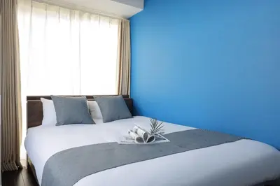 a blue bedroom with a large bed with a blue wall at \u30b9\u30de\u30fc\u30c8 ViLLA \u65d7\u306e\u53f0I\u756a\u9928 in Tokyo