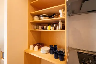 a kitchen with a shelf with dishes and a refrigerator at \u3080\u304f\u306e\u5bb6 \u6d66\u5b89 in Tokyo