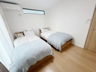 two beds in a room with white walls and wood floors at \u6771\u4eac\u82b3\u83ef\u9a7f\u9986 in Tokyo