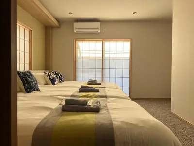a large bed with three pillows on top of it at nestay suite tokyo skytree in Tokyo