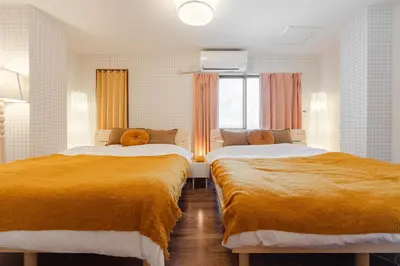 two beds in a room with orange blankets at Casita Dulce in Tokyo