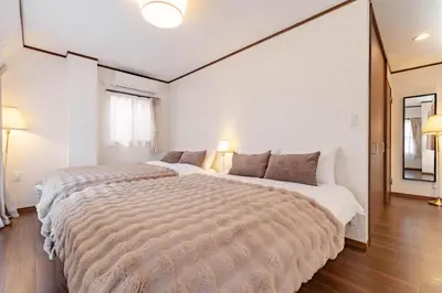 a large bed in a white room with two lamps at Casita Dulce in Tokyo