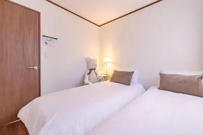 two beds in a small room with white sheets at Casita Dulce in Tokyo