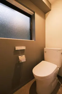a bathroom with a white toilet and a window at IKISUMI HOTEL in Otsuka in Tokyo