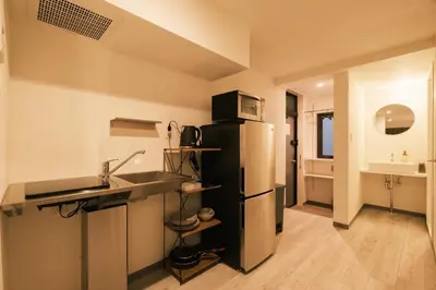 a kitchen with a black refrigerator and a sink at IKISUMI HOTEL in Otsuka in Tokyo