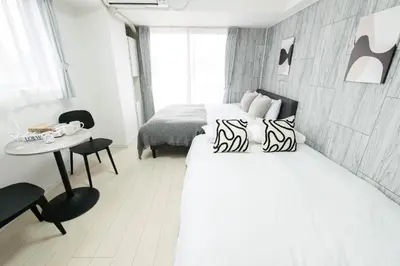 a white bedroom with a bed and a table at Tower View Stay Kinchicho in Tokyo