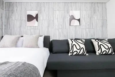 a bedroom with a couch and two paintings on the wall at Tower View Stay Kinchicho in Tokyo