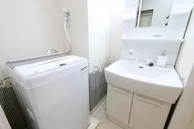 a small white bathroom with a sink and a mirror at Tower View Stay Kinchicho in Tokyo