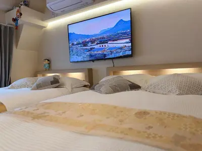 two beds in a bedroom with a tv on the wall at Moto Sakura 502,Asakusa Ueno Great location 2 bedrooms,3 beds,6 Direct access to Narita and Haneda Airports,5 train lines available in Tokyo