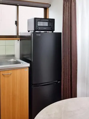 a black refrigerator with a microwave on top of it at \u3068\u307e\u308a\u30fc\u3068Stay \u897f\u4e94\u53cd\u7530 Tomareat Stay Nishi-Gotanda in Tokyo