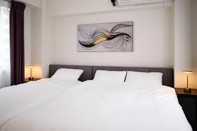 two white beds in a bedroom with a painting on the wall at \u3068\u307e\u308a\u30fc\u3068Stay \u897f\u4e94\u53cd\u7530 Tomareat Stay Nishi-Gotanda in Tokyo