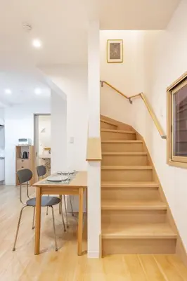 a staircase in a house with a wooden table and chairs at TaroTime Shinjuku Serene Japanese Cottage in Tokyo