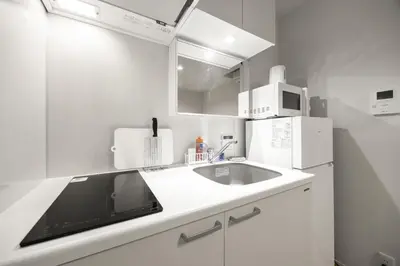 a white kitchen with a sink and a refrigerator at 4\u540d\u5bbf\u6cca \u897f\u65b0\u5bbf\u30a2\u30d1\u30fc\u30c8\u30e1\u30f3\u30c8 in Tokyo