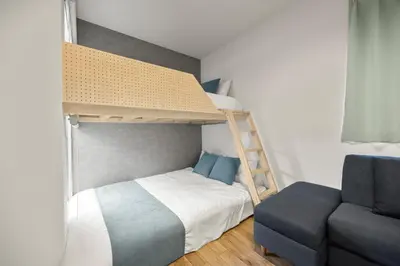 a bedroom with a bunk bed with a ladder and a couch at 4\u540d\u5bbf\u6cca \u897f\u65b0\u5bbf\u30a2\u30d1\u30fc\u30c8\u30e1\u30f3\u30c8 in Tokyo