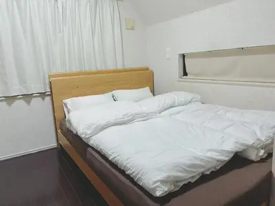 a bed with white sheets and a wooden headboard at \u65b0\u5927\u4e45\u4fdd\u7f8e\u98df\u8857\u9ad8\u7d1a\u6c11\u6cca in Tokyo