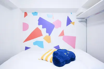 a bedroom with a blue pillow on a bed with a colorful wall at Rio Grande Nishi-Shinjuku 5-chome - Vacation STAY 82770v in Tokyo