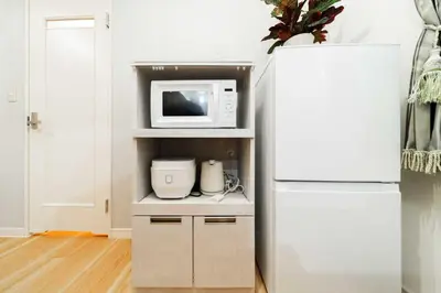 a kitchen with a white refrigerator and a microwave at Nine Lane Nippori II in Tokyo