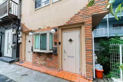 a brick house with a white door and a window at Nine Lane Nippori II in Tokyo
