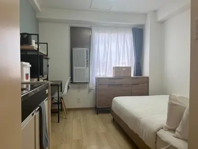a bedroom with a bed and a kitchen with a window at CraftFlat Komagome 503, a compact studio at excellent location in Tokyo