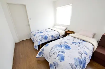 two beds in a room with blue and white sheets at Comore Villa 1F in Tokyo