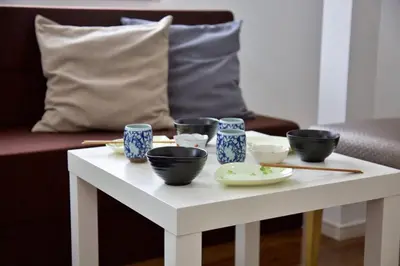 a white coffee table with bowls and chopsticks on it at Comore Villa 1F in Tokyo