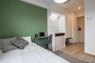 a bedroom with a bed and a desk and a kitchen at CraftFlat Komagome 504, a compact studio at excellent location in Tokyo