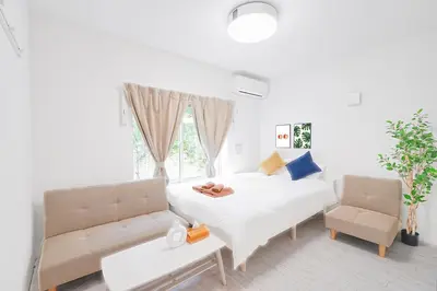 a white bedroom with a bed and a couch at Vivere in Tokyo