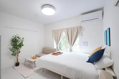 a white bedroom with a large bed and a couch at Vivere in Tokyo