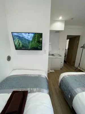 two beds in a room with a tv on the wall at Yotsuya, 10 seconds from Yotsuya Sanchome Station, in the heart of Shinjuku in Tokyo