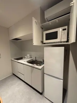 a small kitchen with a microwave and a refrigerator at PRISM Inn Kagurazaka in Tokyo