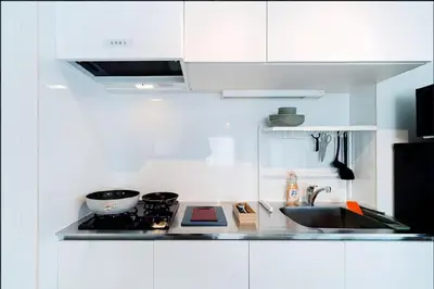 a white kitchen with a stove and a sink at Nine Lane Omori in Tokyo