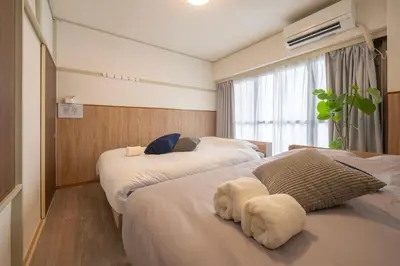 a hotel room with two beds and a window at 15 min Ikebukuro Tokyo 2-BR Apartment in Tokyo