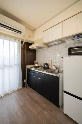 a kitchen with black cabinets and a white refrigerator at 15 min Ikebukuro Tokyo 2-BR Apartment in Tokyo