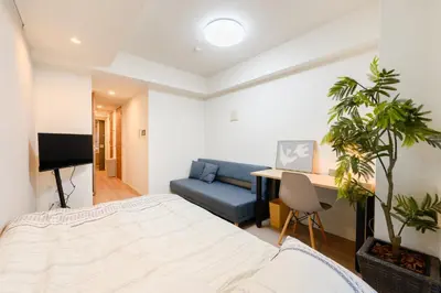 a bedroom with a bed and a blue couch at アルファサイト御茶ノ水 - Historic Ochanomizu Stay - Near Akihabara & Imperial Palace - JR & Subway Access in Tokyo