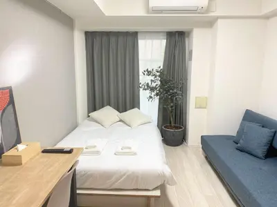 a hotel room with a white bed and a blue couch at アルファサイト御茶ノ水 - Historic Ochanomizu Stay - Near Akihabara & Imperial Palace - JR & Subway Access in Tokyo