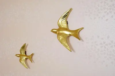 two gold birds earrings on a pink background at Hagi in Tokyo