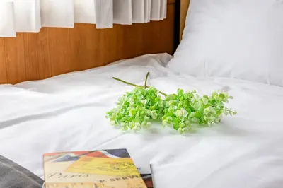 a book and a bouquet of green flowers on a bed at \u30e2\u30f3 \u30b7\u30e3\u30c8\u30fc\u4e2d\u91ce\u5e73\u548c\u306e\u68ee in Tokyo