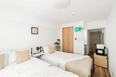 two beds in a room with white walls at Shinjuku Center Apart ment in Tokyo