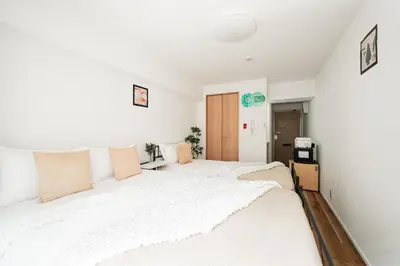 a white bedroom with two beds and a tv at Shinjuku Center Apart ment in Tokyo