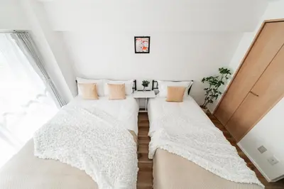 two beds in a room with white walls at Shinjuku Center Apart ment in Tokyo