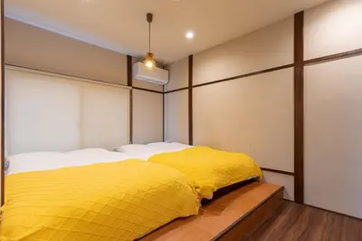 two beds in a room with yellow sheets at \u548c\u6c17\u4f1a\u3005\u690e\u540d\u753a Wakiaiai Shiinamachi in Tokyo